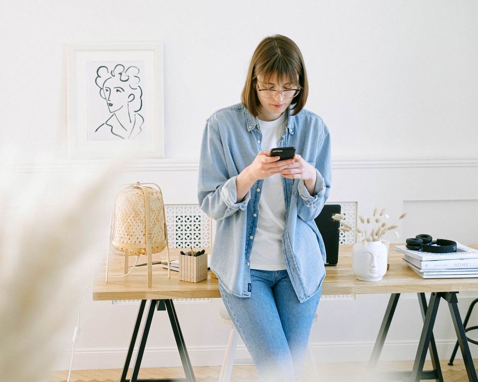 A person reading on their phone in a bright home office
