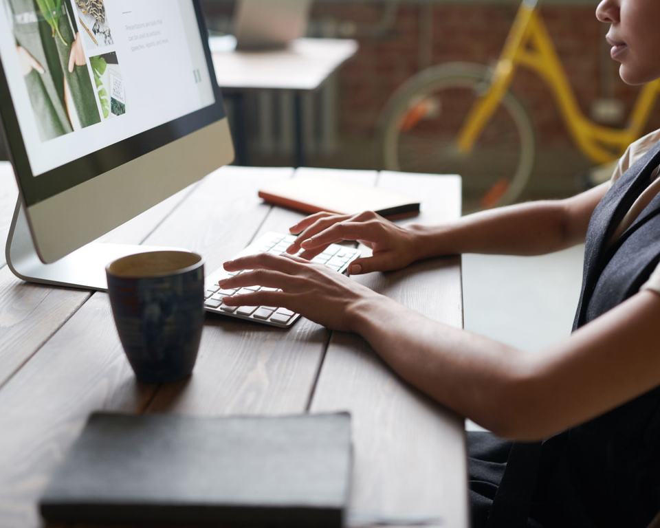 Hands typing on a keyboard in front of a desktop computer