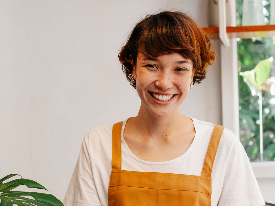 A smiling café worker using a tablet at the counter